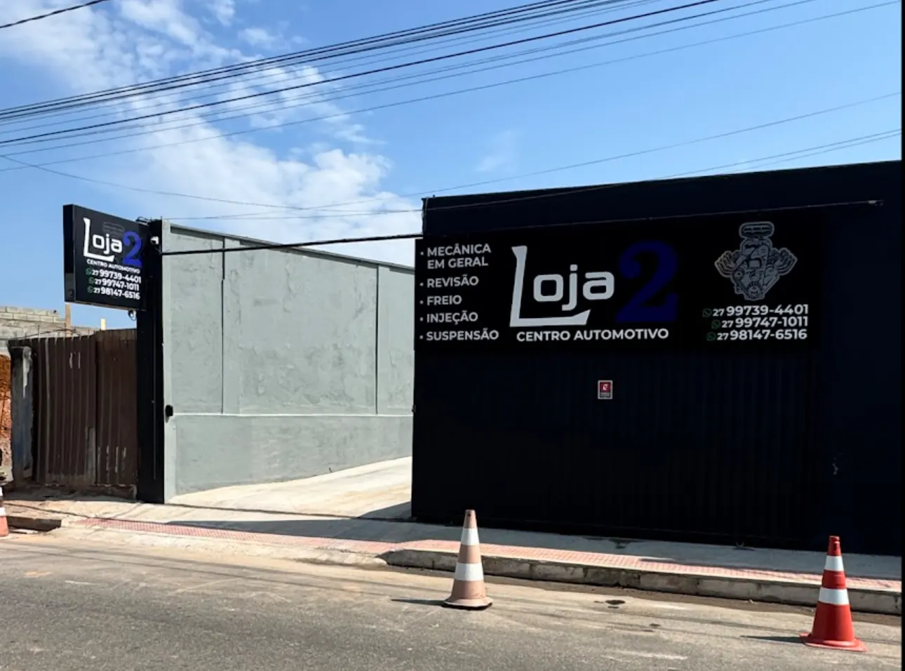Fachada preta da Loja 2 Centro Automotivo em Guarapari, com a placa da oficina, a lista de serviços e os telefones